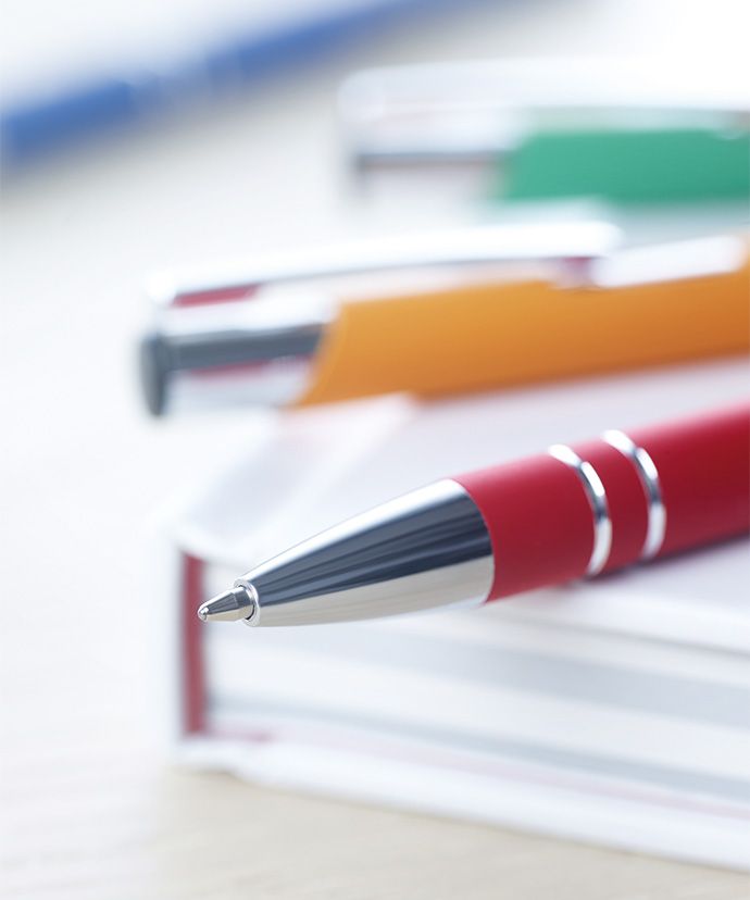 Metallpennor i olika färger som ligger på en bok